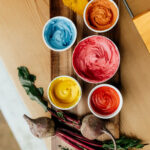 A colorful selection of frosting bowls, all made using the India Tree Nature's Colors Decorating Set for natural food coloring.