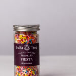 India Tree Nature's Colors Fiesta Dye-Free Sprinkles in a 3 oz glass jar with scattered sprinkles